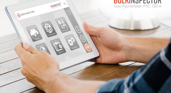 One person operates the BULKINSPECTOR pycnometer using a tablet and the start menu is displayed. Here you can choose whether you want to carry out a measurement, set the sample or measurement parameters, calibrate the device, display the results or change general settings.