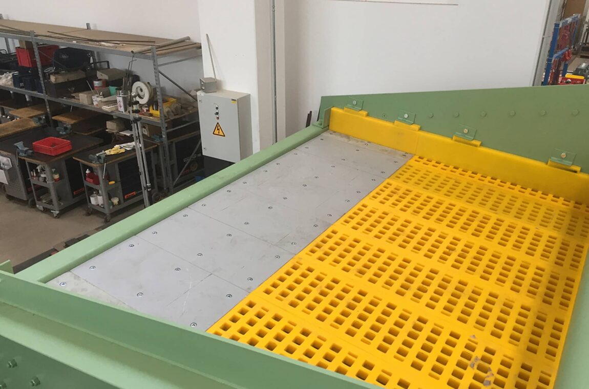 Linear vibratory screening machine HG 22-5_76-II WS - feed side. The machine is in production, you can see the yellow polyurethane screens