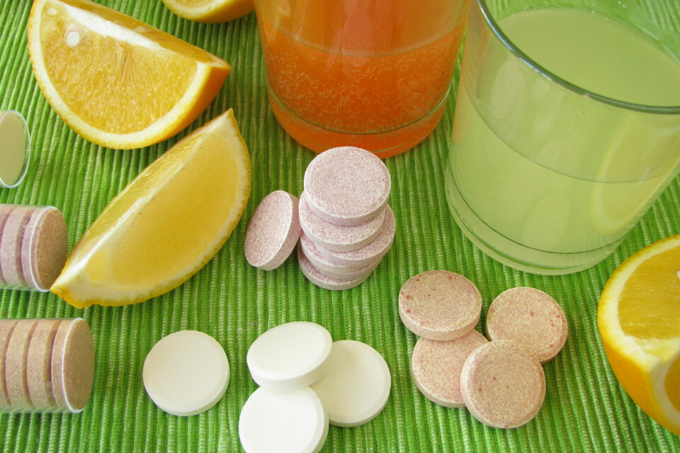 Various sherbet powder tablets, lemon wedges and 2 glasses of sherbet already dissolved in water