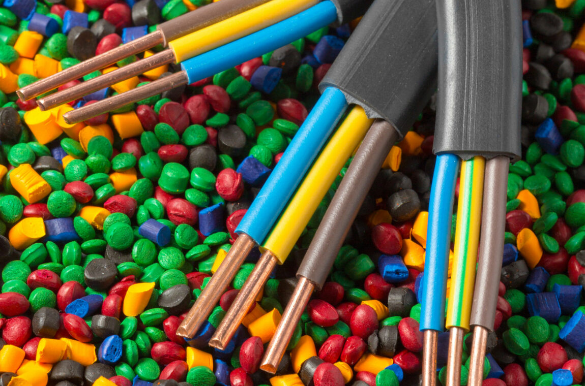 3 plastic-coated copper cables lie on colored polymer granules